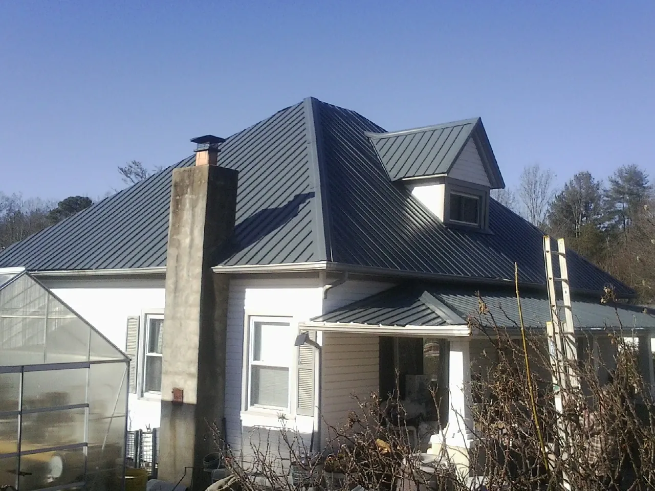 Dark blue standing seam metal roof on a white farmhouse with dormer — Slate & Tile Roof Repair by Roofing Brothers in Warner Robins