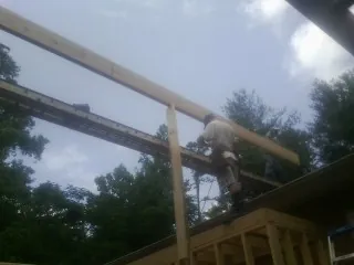 Carpenter setting a ridge beam over a new addition frame — Ice Dam Removal by Roofing Brothers in Warner Robins