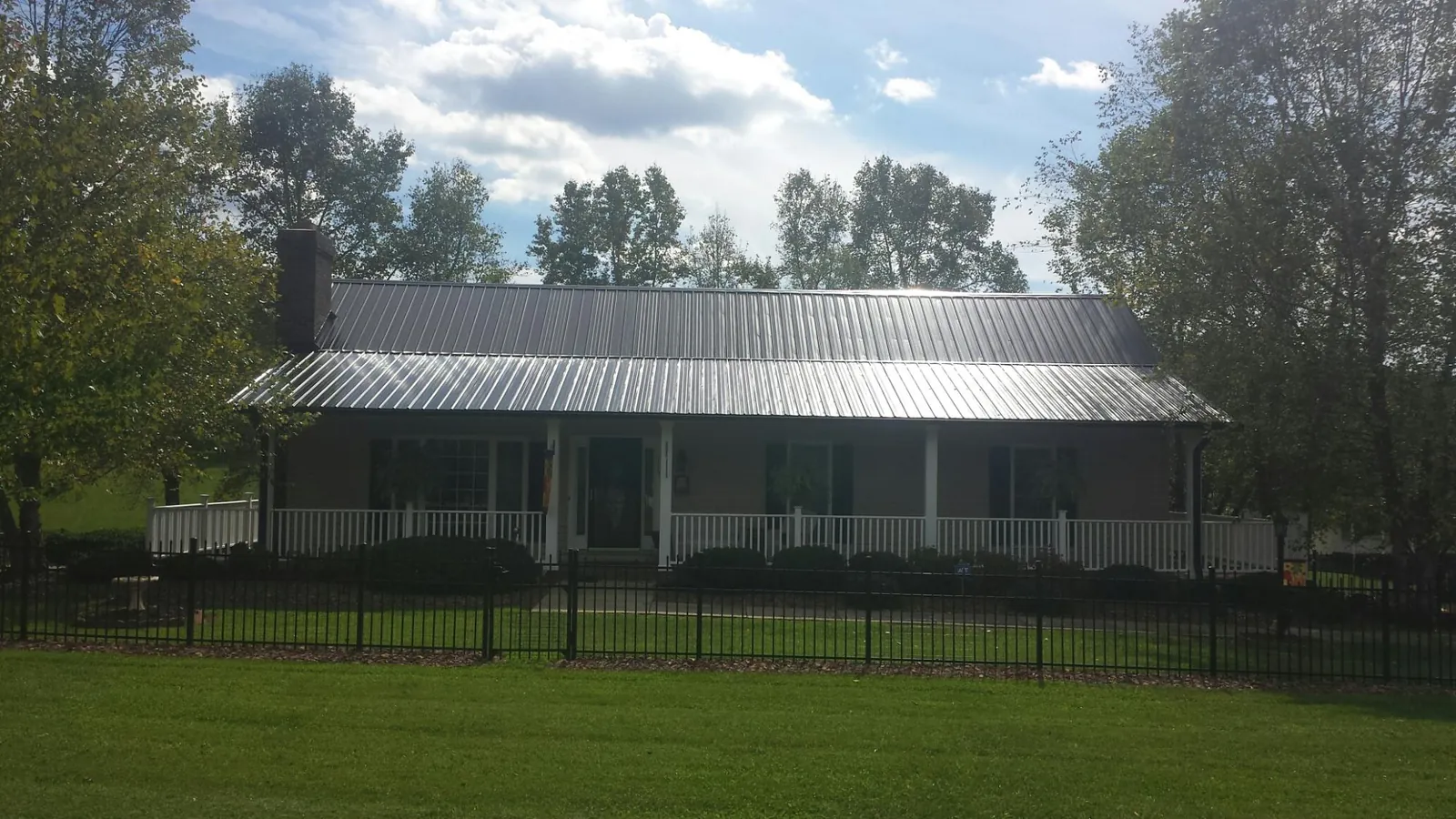 Gray metal roof on a brick ranch with a full width front porch — Gutter Guard Installation work by our crew in Warner Robins