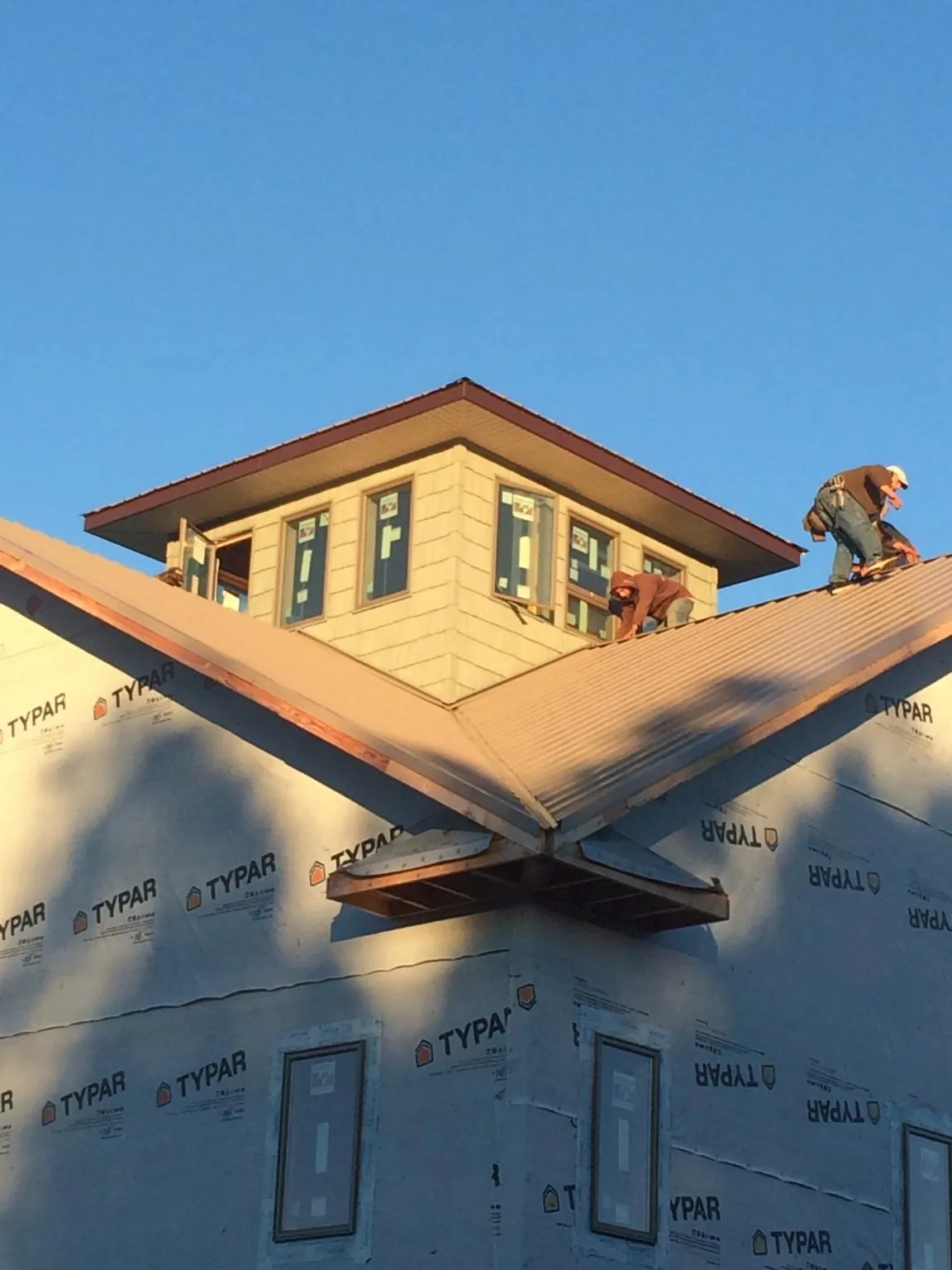 Roofers working around a rooftop cupola on a new metal roof at sunset — Roof Waterproofing in Warner Robins by Roofing Brothers